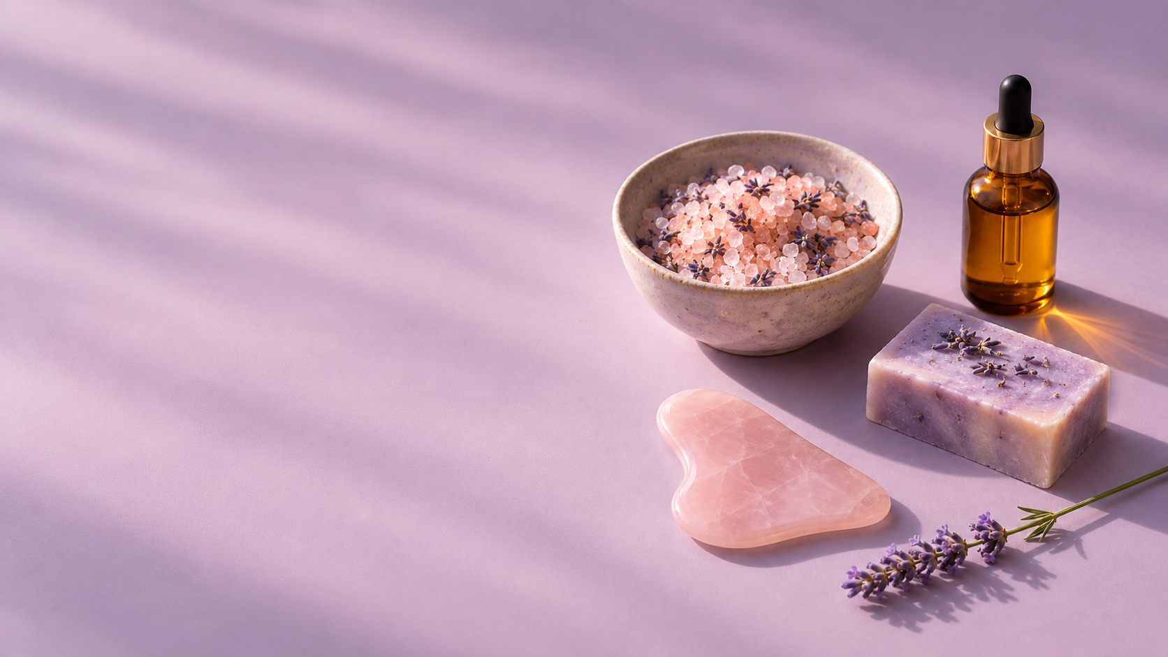 Wide lilac spa still life with bath salts, amber oil bottle, lavender soap and rose quartz gua sha
